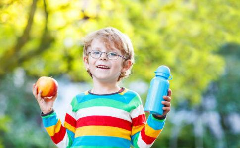 Kind hält Apfel und Trinkflasche in den Händen