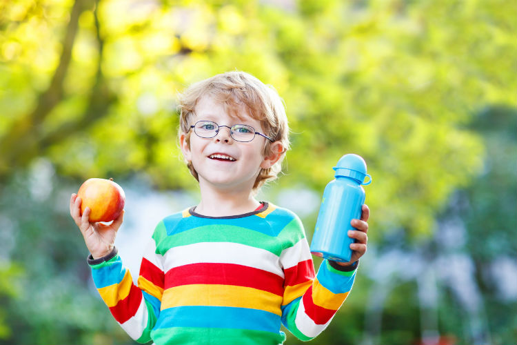 Kind hält Apfel und Trinkflasche in den Händen