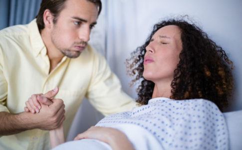 Mann tröstet schwangere Frau die eine Wehe hat