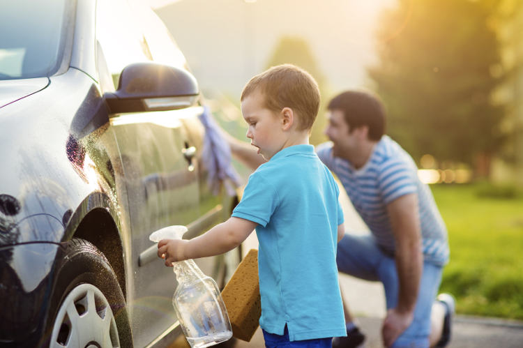 Kind wäscht Auto zusammen mit Vater