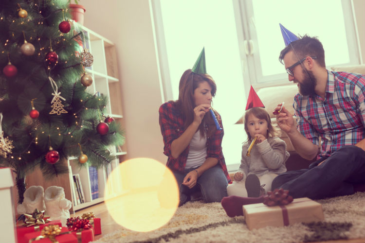 Eltern, die mit ihrem Kind gemeinsam Silvester im Wohnzimmer feiern