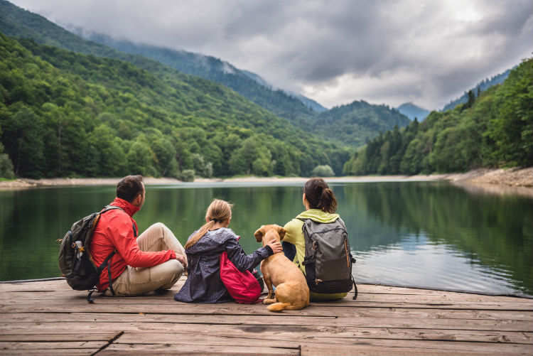 Familie mit Hund macht eine Wanderpause am See