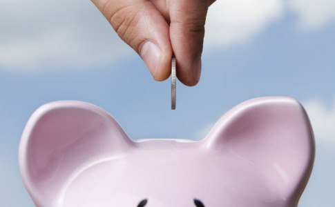 Geld wird in Sparschwein gesteckt