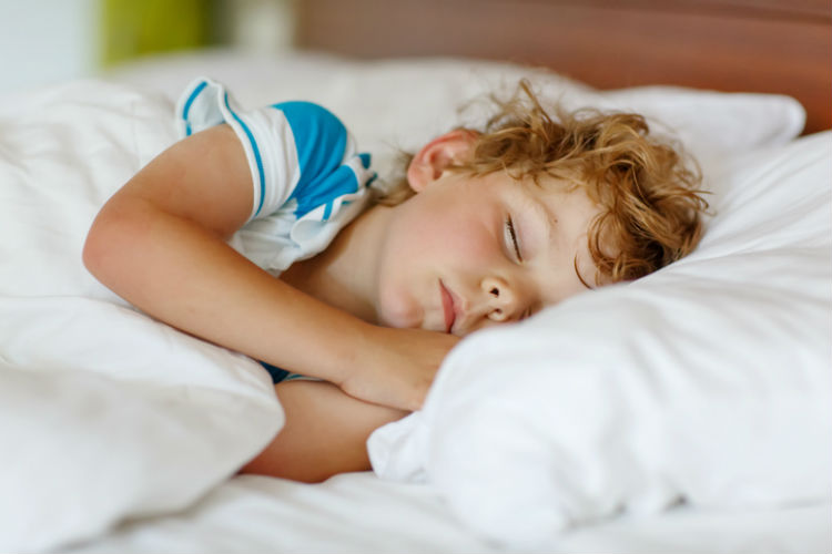 Kleiner Junge liegt im Bett und schläft