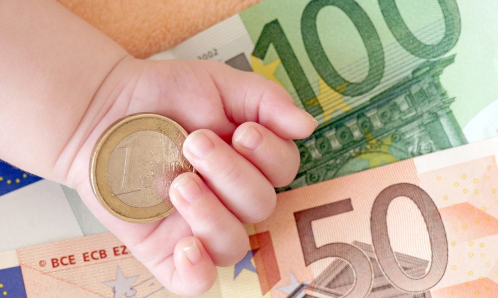 Euronoten und Geldstück mit einer Babyhand im Bild