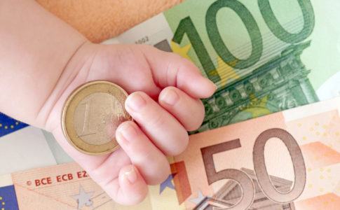 Euronoten und Geldstück mit einer Babyhand im Bild