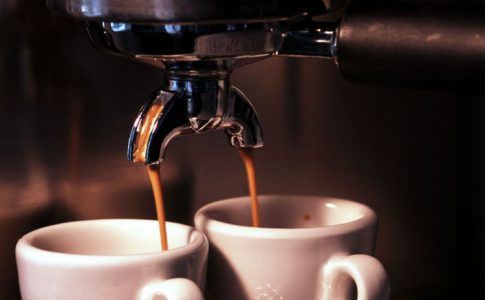 zwei Tassen unter laufender Kaffeemaschine