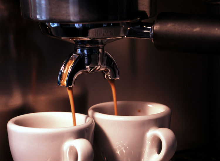 zwei Tassen unter laufender Kaffeemaschine