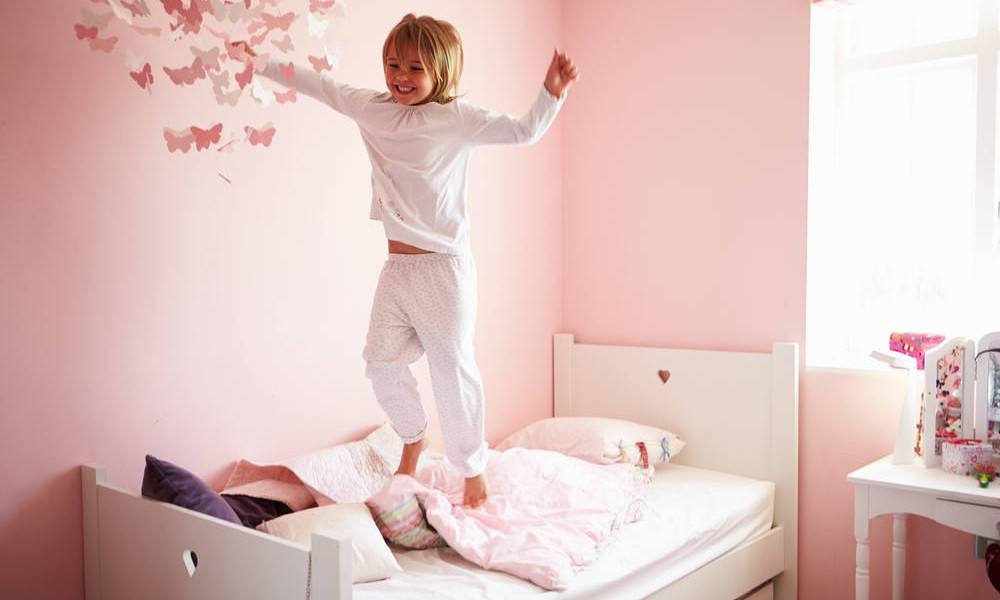 Mädchen springt auf ihrem Bett