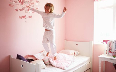 Mädchen springt auf ihrem Bett