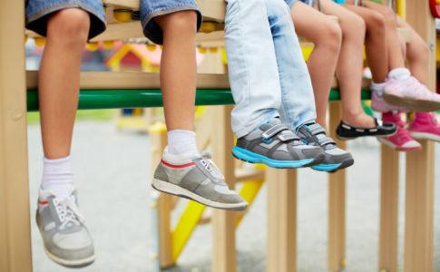 Kinderbeine mit unterschiedlichen Kinderschuhen an den Füßen