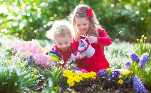 Kinder in Blumenbeet am Blumen gießen - Lieblingsplatz im Garten