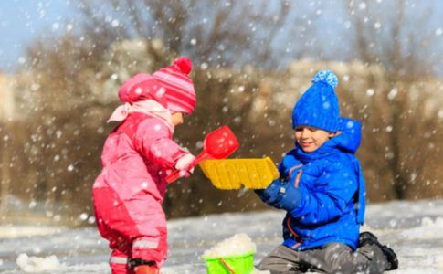 Kleinkinder spielen mit Spielzeug im Schnee