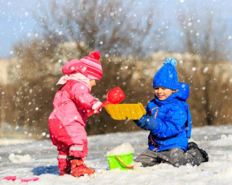 Kleinkinder spielen mit Spielzeug im Schnee