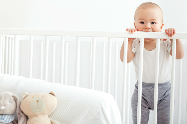 Baby steht in einem Babybett