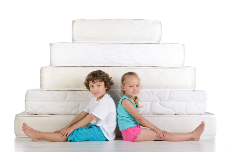 Zwei Kinder die vor Matratzen sitzen