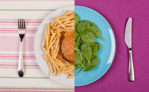 Ein Teller, auf dem auf der einen Seite Fast Food und auf der anderen Seite Salat zu sehen ist