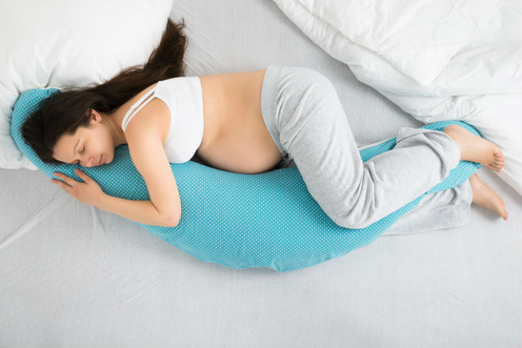 Schwangere Frau, die mit einem Stillkissen seitlich schläft