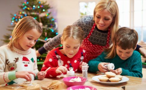 Drei Kinder backen mit ihrer Mutter Kekse