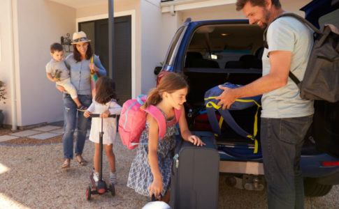 Familie packt ihre Koffer in ein Auto, um in den Urlaub zu fahren
