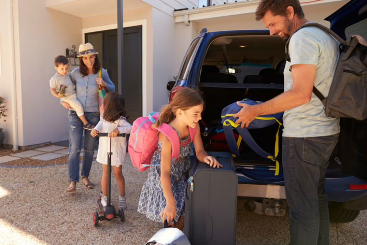 Familie packt ihre Koffer in ein Auto, um in den Urlaub zu fahren