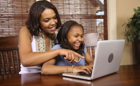 Mutter sitzt mit der Tochter am Laptop