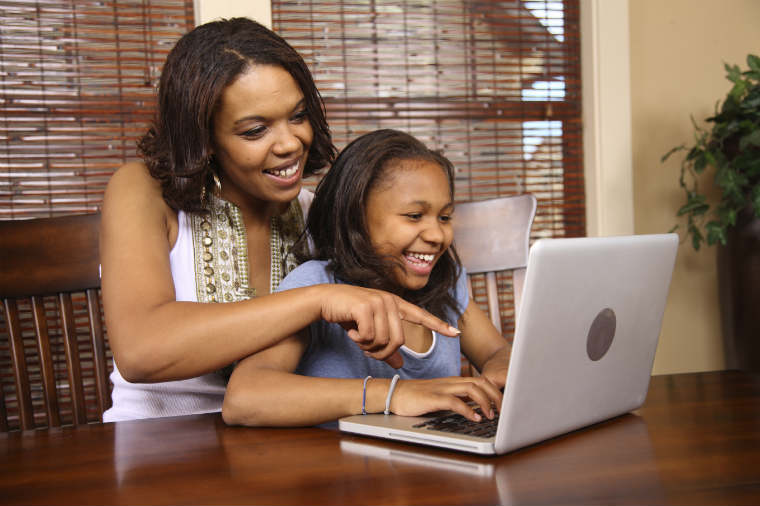 Mutter sitzt mit der Tochter am Laptop