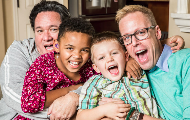 Homosexuelles Paar auf lustigem Familienfoto mit ihren zwei Pflegesöhnen