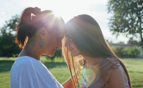 Mutter und Tochter Stirn an Stirn im Sonnenschein