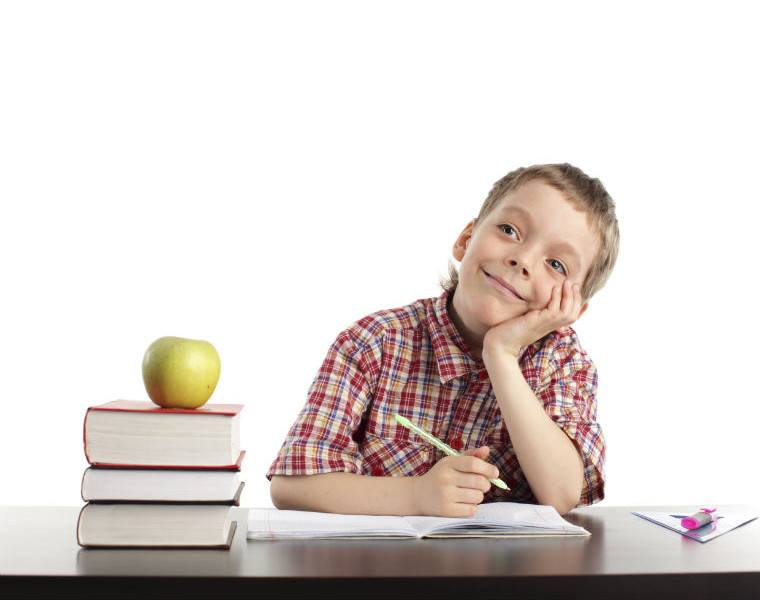 Schulkind mit Büchern und Apfel neben sich