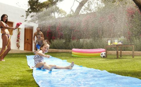Familie hat Spaß bei Spielen mit Wasser im Garten