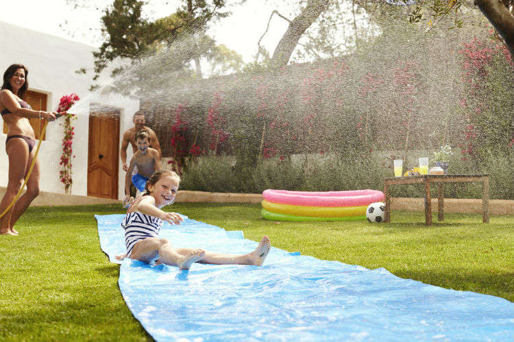 Familie hat Spaß bei Spielen mit Wasser im Garten