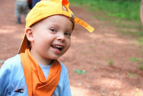 Kind lachend mit gelber Mütze