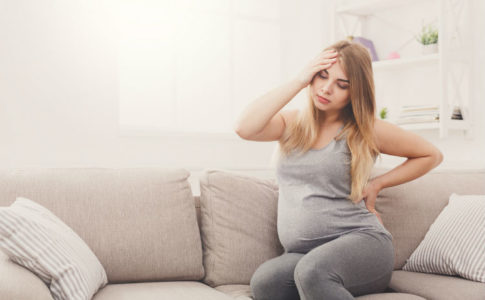 Schwangere Frau auf dem Sofa mit Beschwerden