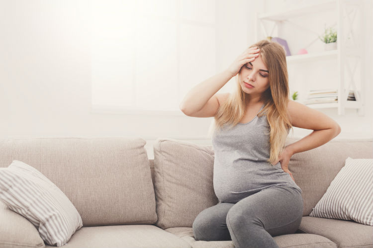 Schwangere Frau auf dem Sofa mit Beschwerden