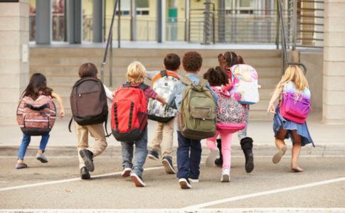 Kinder, die mit Schulranzen zur Schule laufen