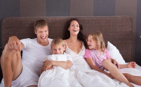 Familie gemeinsam im Hotelbett Ihres Familienzimmers