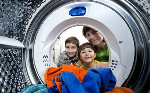 Kinder schauen in eine Waschmaschine.