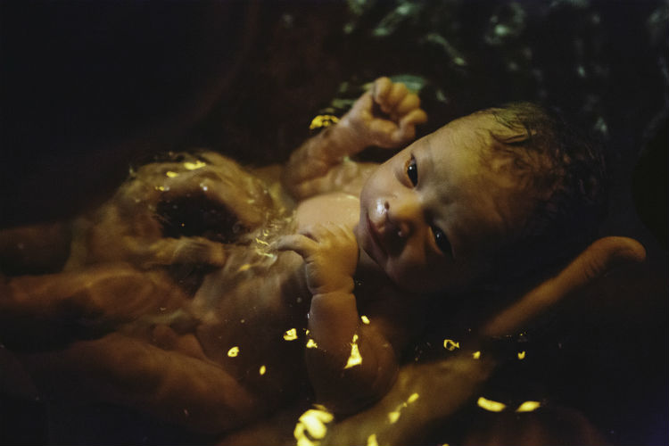 Neugeborenes wird im Wasser von Mutter gehalten