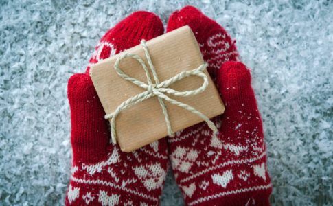 weihnachtliche Handschuhe halten Geschenk
