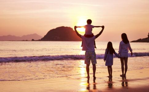 Glückliche Familie im Urlaub am Strand bei Sonnenuntergang