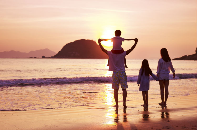Glückliche Familie im Urlaub am Strand bei Sonnenuntergang