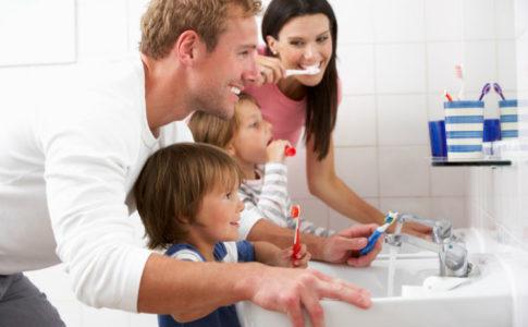 Eltern putzen gemeinsam mit ihren Kleinkindern die Zähne im Bad