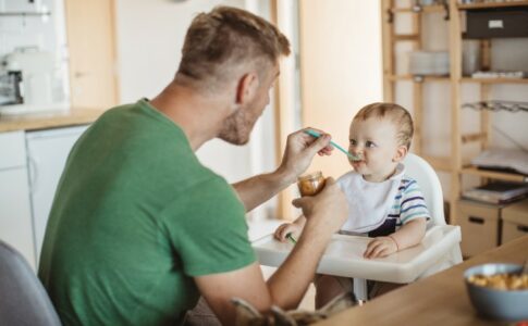 Ein Mann füttert sein Baby.