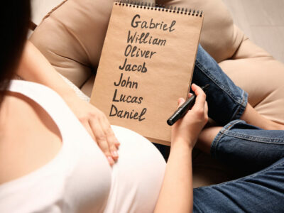 Eine schwangere Frau schreibt viele Baby-Namen auf einen Notizblock