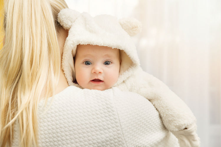 Mutter trägt Baby auf dem Arm, das warm angezogen ist