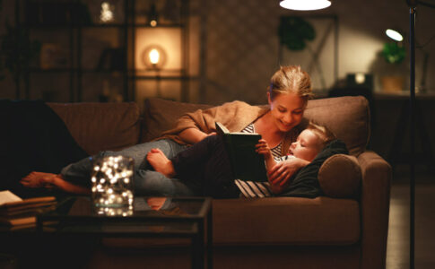 Eine Mutter liest ihrem Kind bei angenehmer Beleuchtung etwas vor.