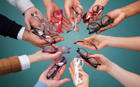 Mehrere Brillengestelle werden von verschiedenen Händen gehalten