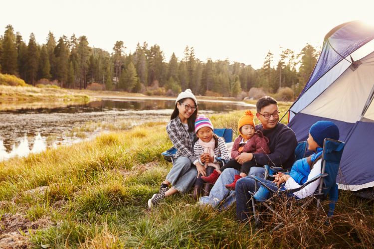 Eine Familie sitzt während des Camping-Ausfluges vor einem Zelt