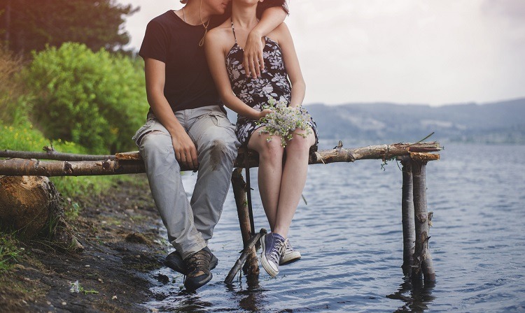 ein junges Paar sitzt auf einem Steg am See